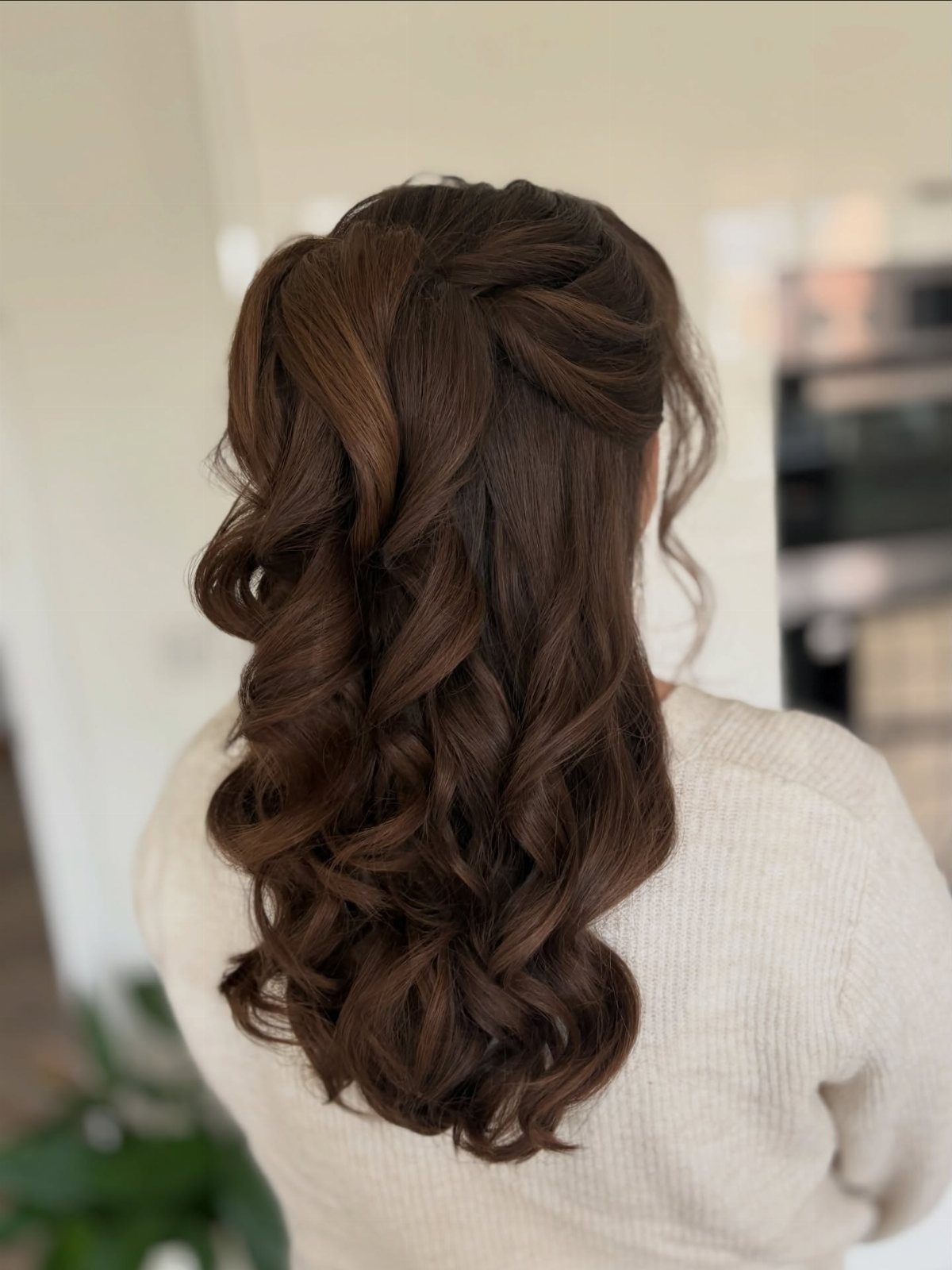 Curled brunette hair pinned at the crown and falling in soft curls