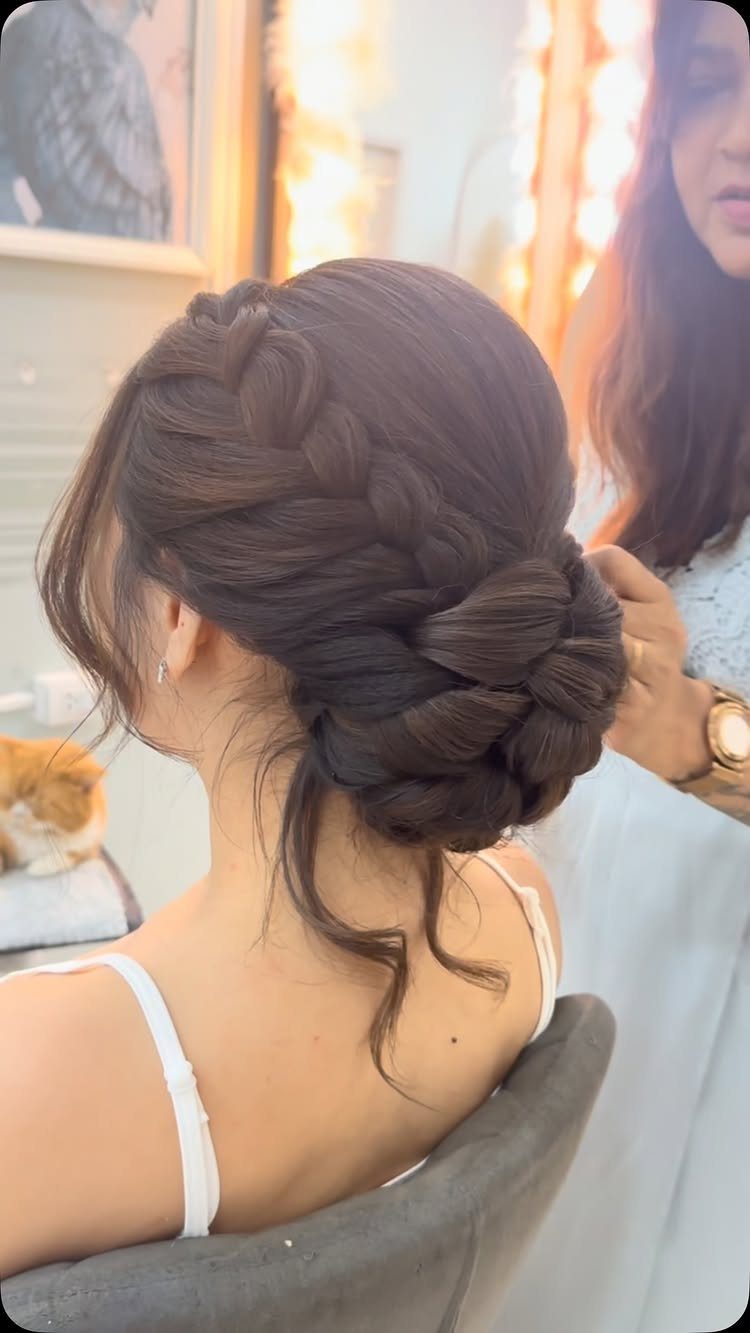 Dark braided bun gathered low at the back of a seated woman's head