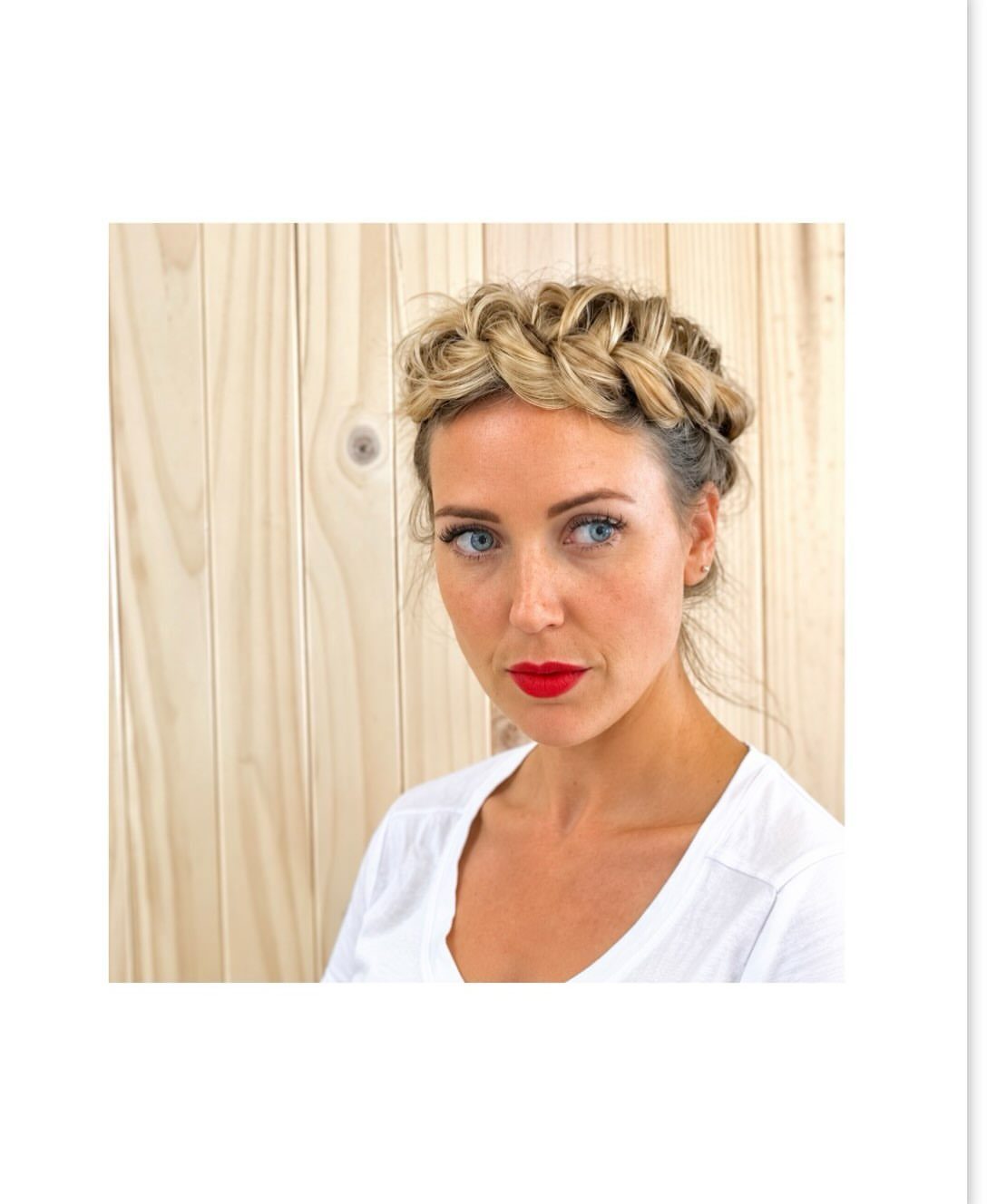 Woman wearing a blonde braided crown updo against pale wooden boards