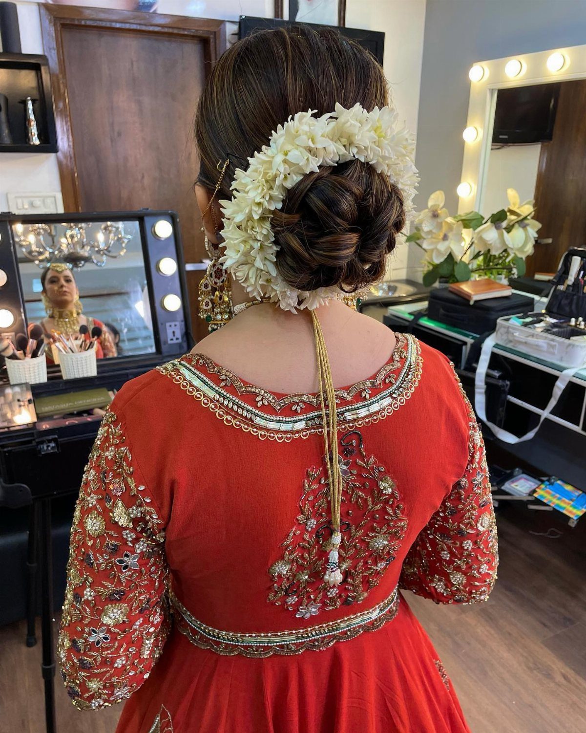 Large twisted bridal bun decorated with white flowers on a woman in a red dress
