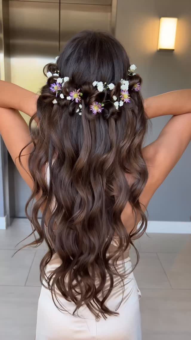 Partly pinned wedding hairstyle with long waves and small white and purple flowers