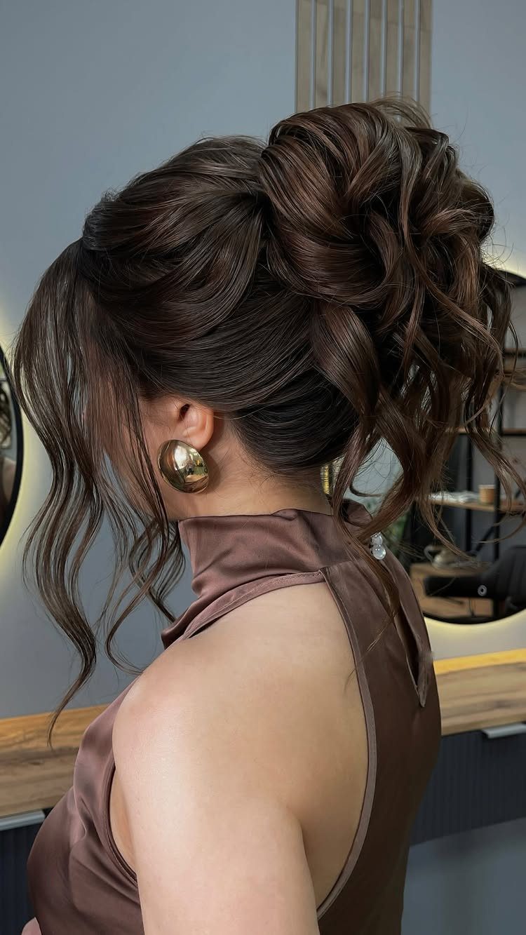 Woman showing a voluminous braided high bun with loose face-framing strands