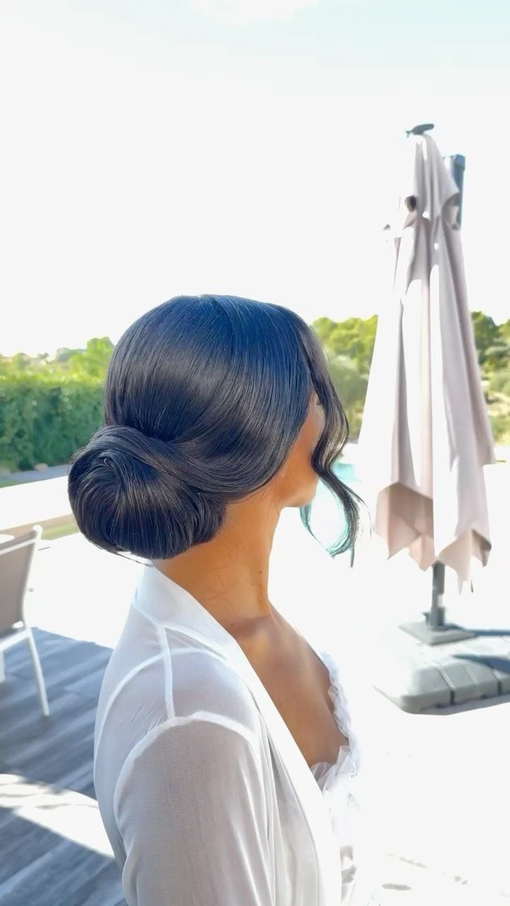 Woman with sleek low chignon and loose tendril on a sunny terrace