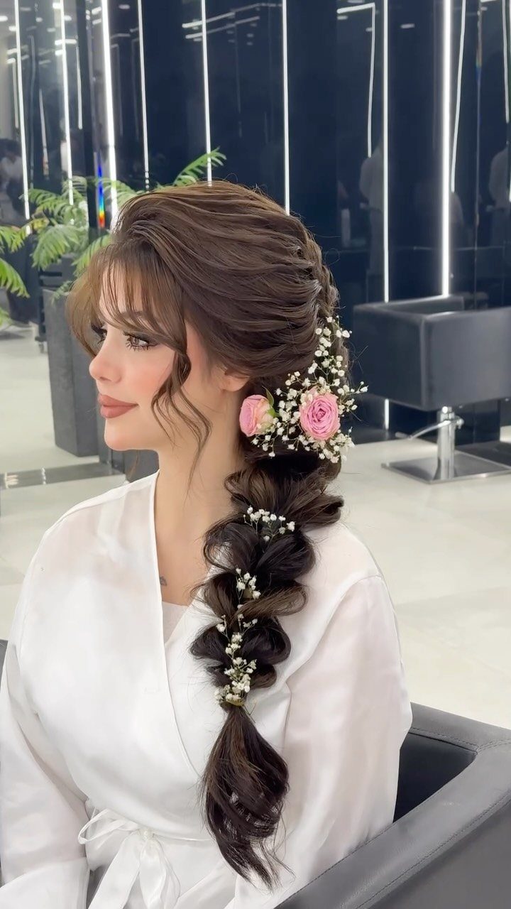 Woman wearing a long flower-adorned braid over one shoulder