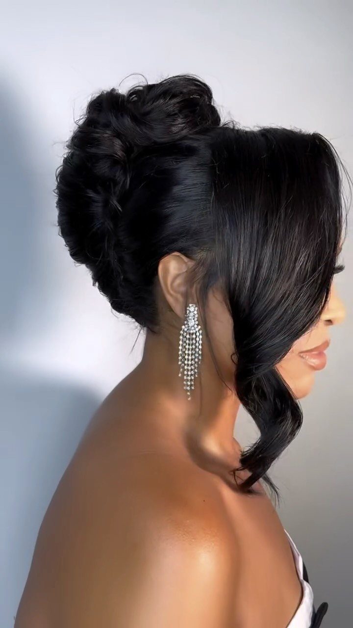 Woman wearing a voluminous dark updo with a curled face-framing tendril