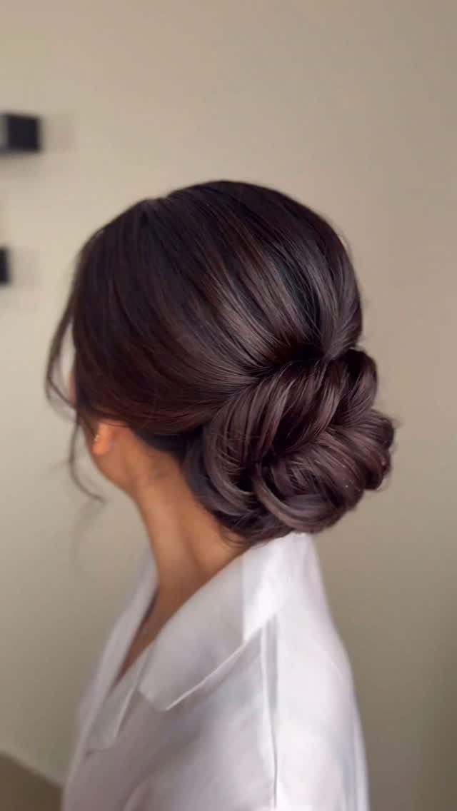 Woman with smooth dark hair arranged in a low twisted bun