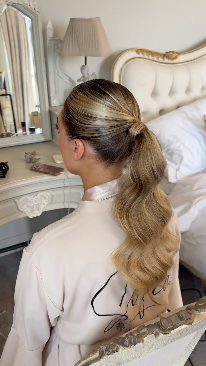 Sleek blonde ponytail falling in long waves over a satin robe