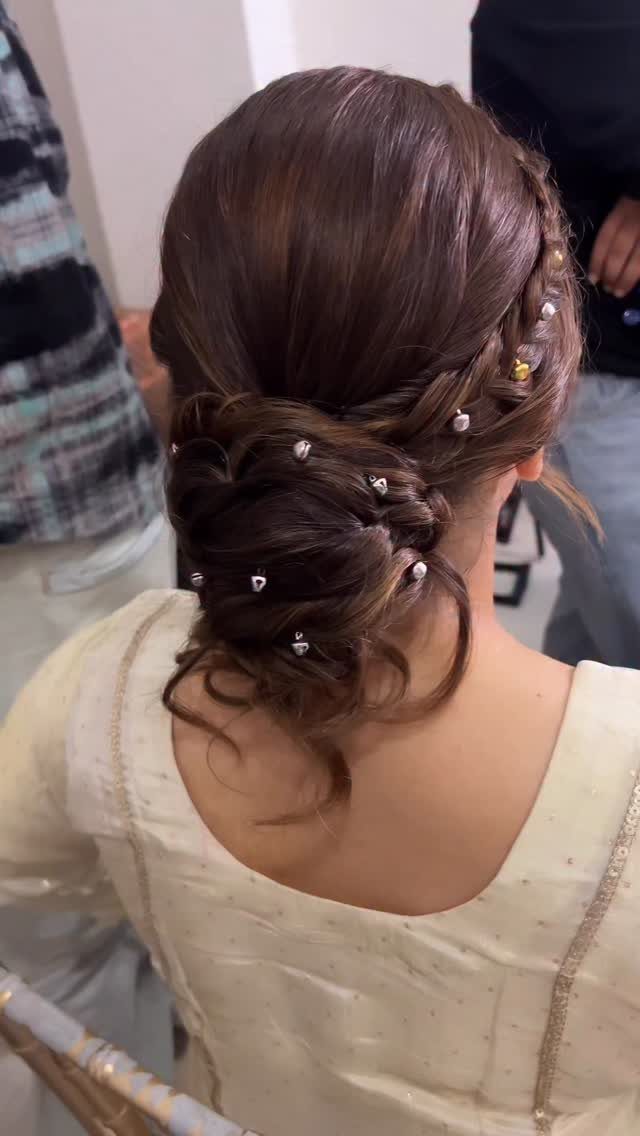 Low twisted brown updo decorated with small pearl-like pins