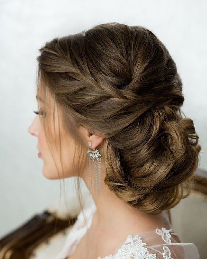 Bride wearing a large low bun wrapped with broad crossed braids