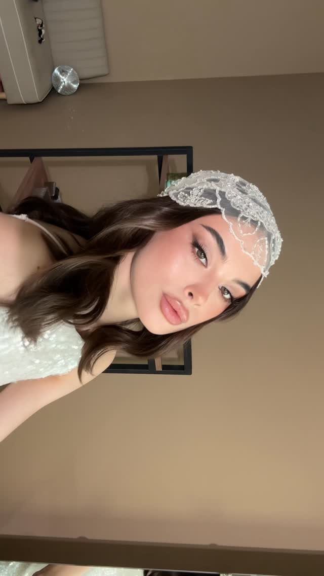 Woman wears long flowing waves with a white lace Juliet cap