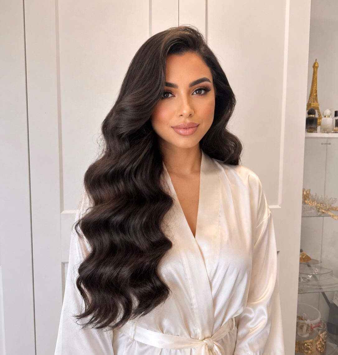 Woman wearing long, glossy dark hair in loose waves over one shoulder
