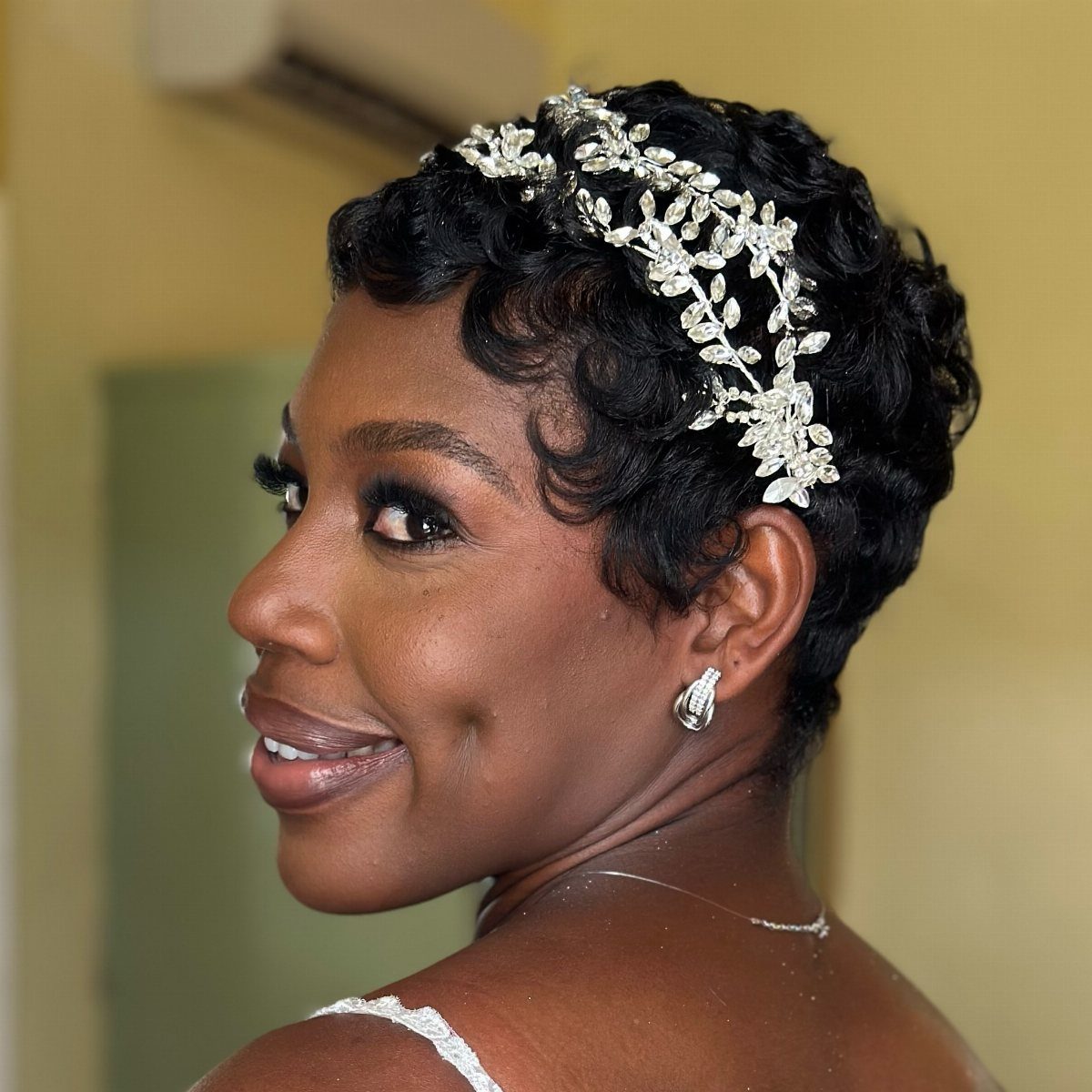 Woman with short curled hair wearing a jeweled silver statement headband